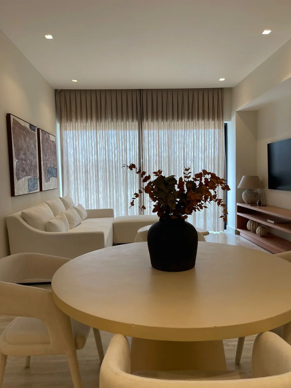 Photographie de l'espace ouvert de la résidence témoin : la table à manger au premier plan, le salon et les baies de la terrasse au fond.